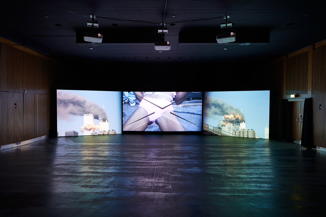 A close-up of a Black person wearing pink underwear is shown between two images of burning towers.