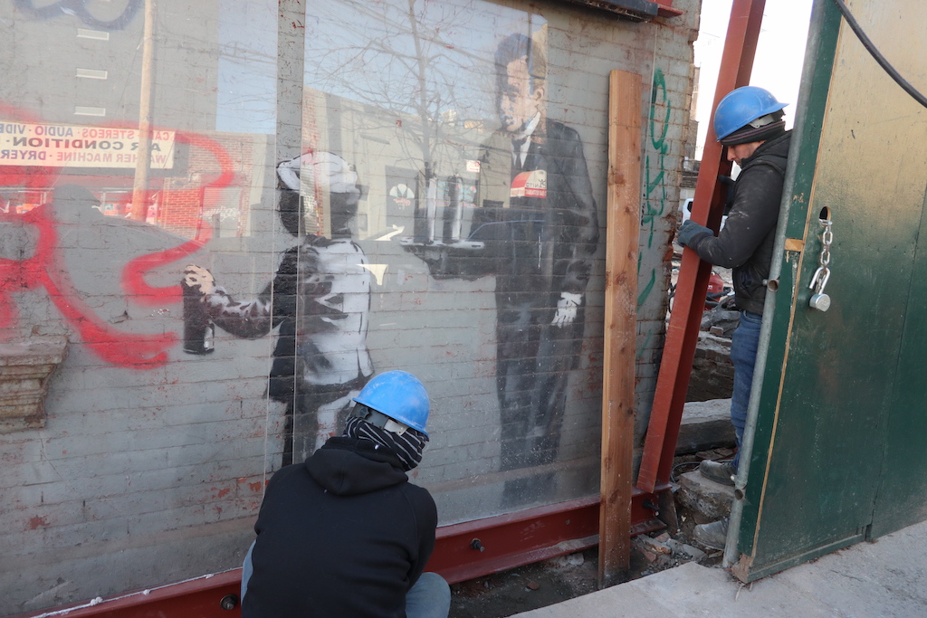 Workers prepare Banksy's wall mural for transportation.
