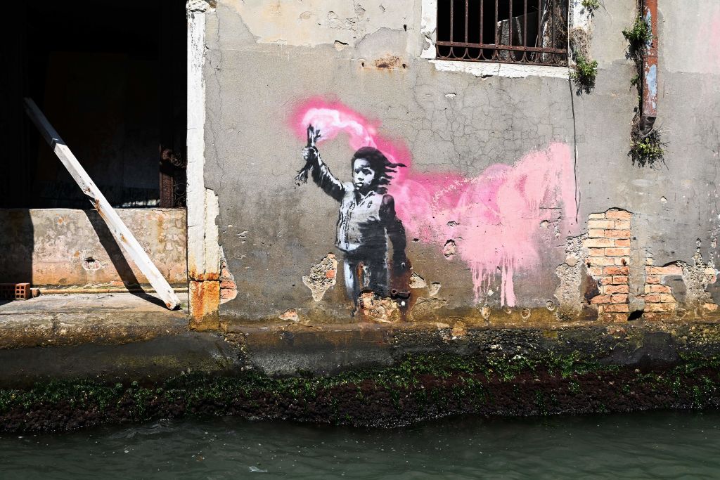 A mural by British street artist Banksy, of a child holding a pink flare, is pictured on August 27, 2019 on a building in Venice. (Photo by Vincenzo PINTO / AFP) / RESTRICTED TO EDITORIAL USE - MANDATORY MENTION OF THE ARTIST UPON PUBLICATION - TO ILLUSTRATE THE EVENT AS SPECIFIED IN THE CAPTION (Photo credit should read VINCENZO PINTO/AFP via Getty Images)