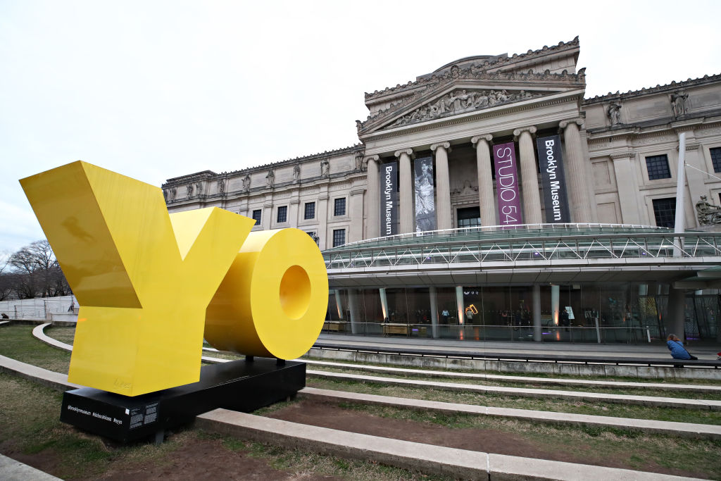 A museum facade with a giant sculpture reading 'YO' in bright yellow letters.