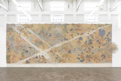 installation shot of a large-scale yellowish abstract artwork with diagonal which slashes on the wall of a gallery