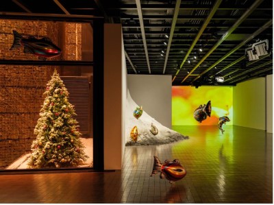 An installation featuring a Christmas tree with a blow-up fish suspended over it.