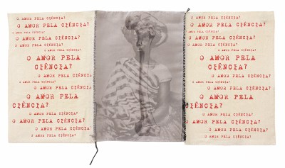 A triptych in which the middle panel is an image of a Black woman superimposed with a bone. Sewn to either side are white panels that repeatedly bear the phrse 'O AMOR PELA CIÊNCIA?'
