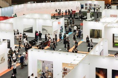 View of art fair booths from overhead with visitors milling about.