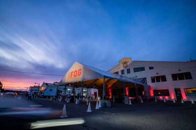 Exterior view of a building, at dusk, with a built canopy reading FOG.